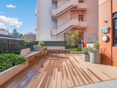 Rooftop terrace with wooden decking, built-in seating, planters, and city views at UniLodge Auckland Central.