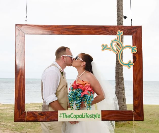 A couple kissing on a framed decor at Copamarina Weddings
