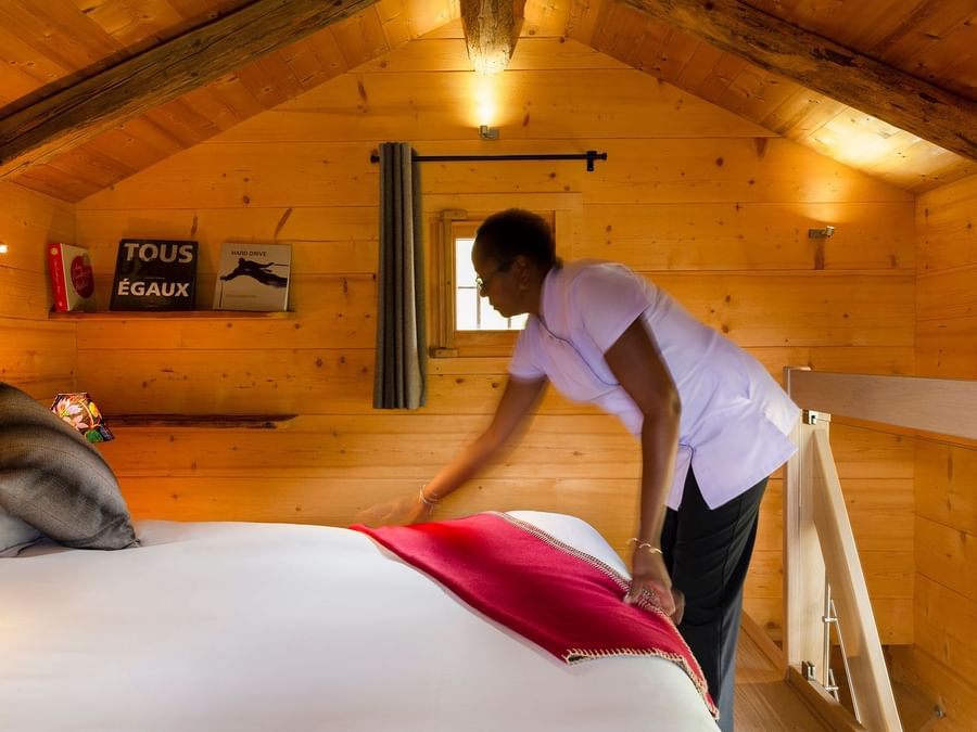 A maid making room bed at Chalet hotel la ferme du chozal
