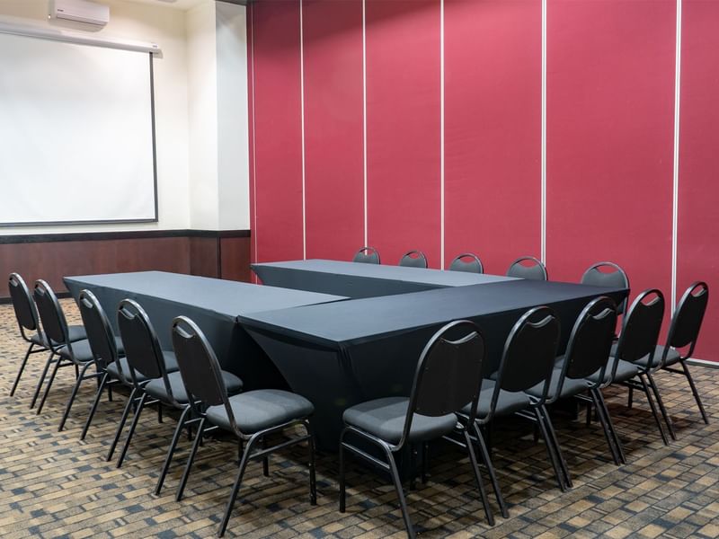 Salon A featuring a large black table set against a projector screen at Fiesta Inn Tepic
