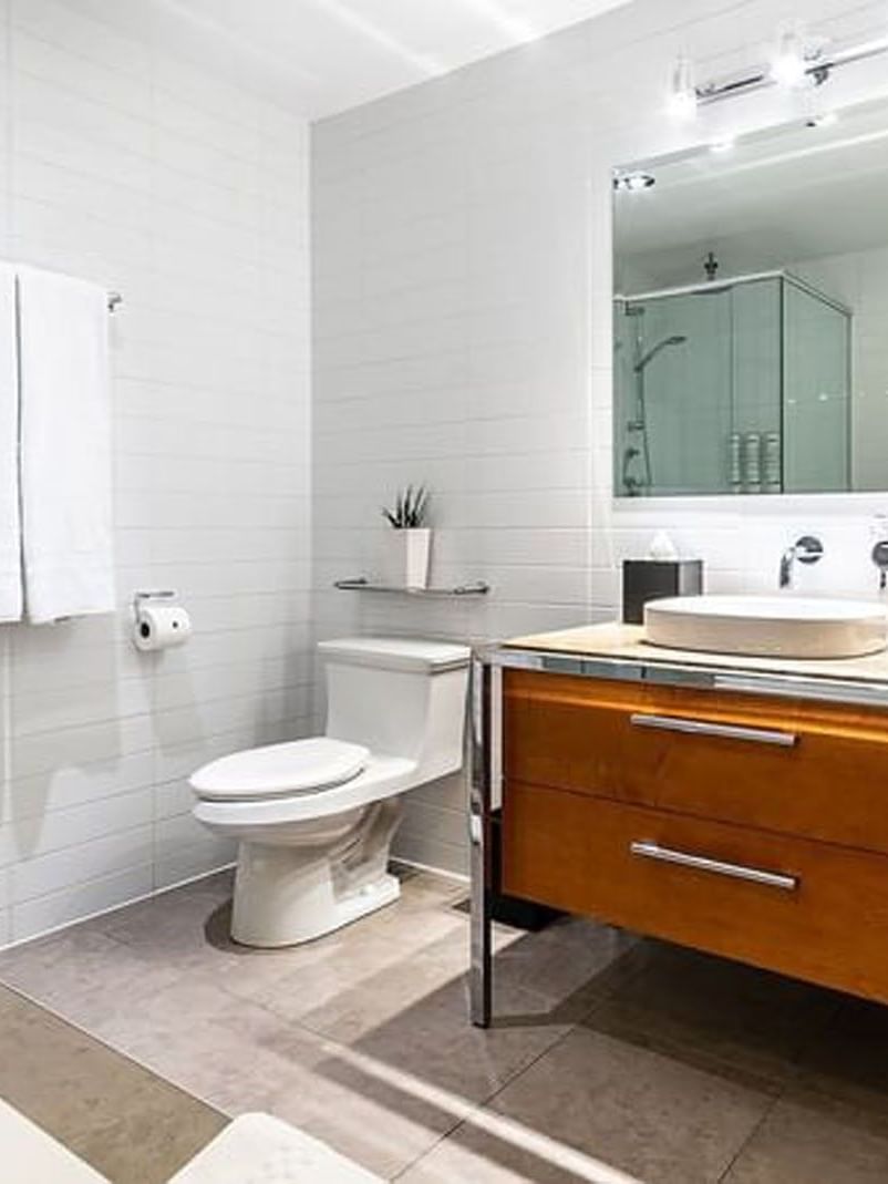 Salle de bains moderne avec double vasque, toilettes et cabine de douche au Penthouse Crescent du Warwick Le Crystal - Montréal.