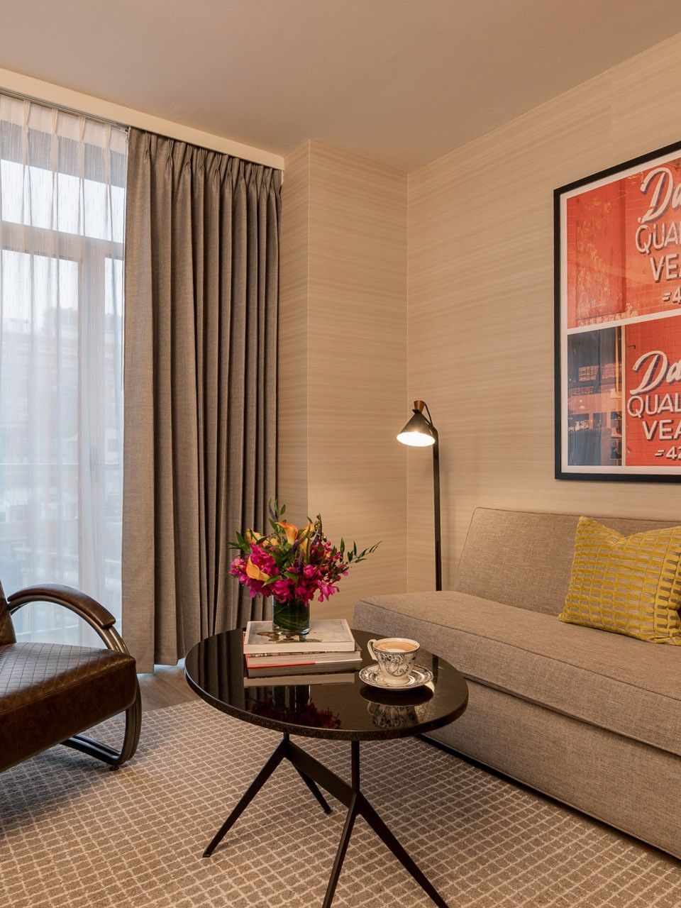 Manhattan Suite living area with beige sofa, vintage armchair, and retro artwork at Gansevoort Meatpacking NYC - NEW.