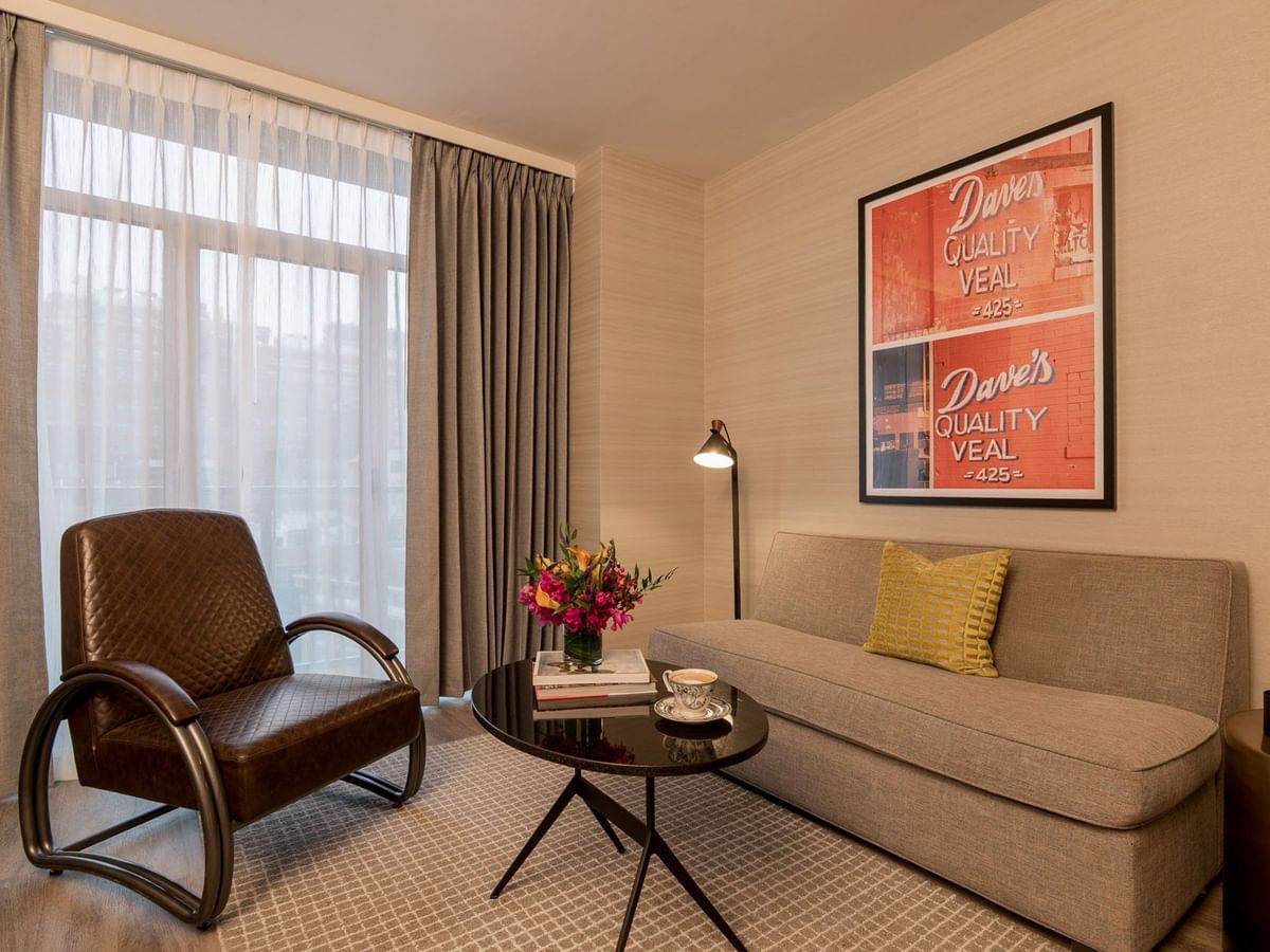 Manhattan Suite living area with beige sofa, vintage armchair, and retro artwork at Gansevoort Meatpacking NYC - NEW.