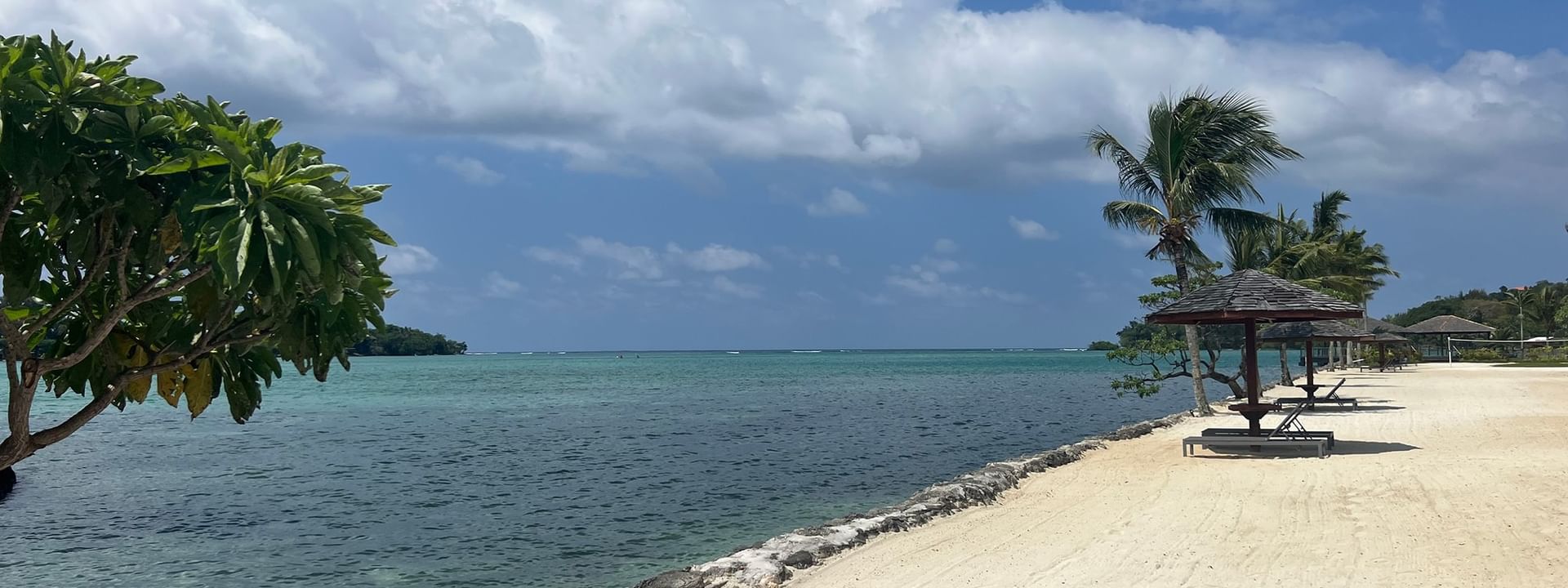 Sandy beach with ocean view and tropical trees at Warwick Le Lagon - Vanuatu in Efate