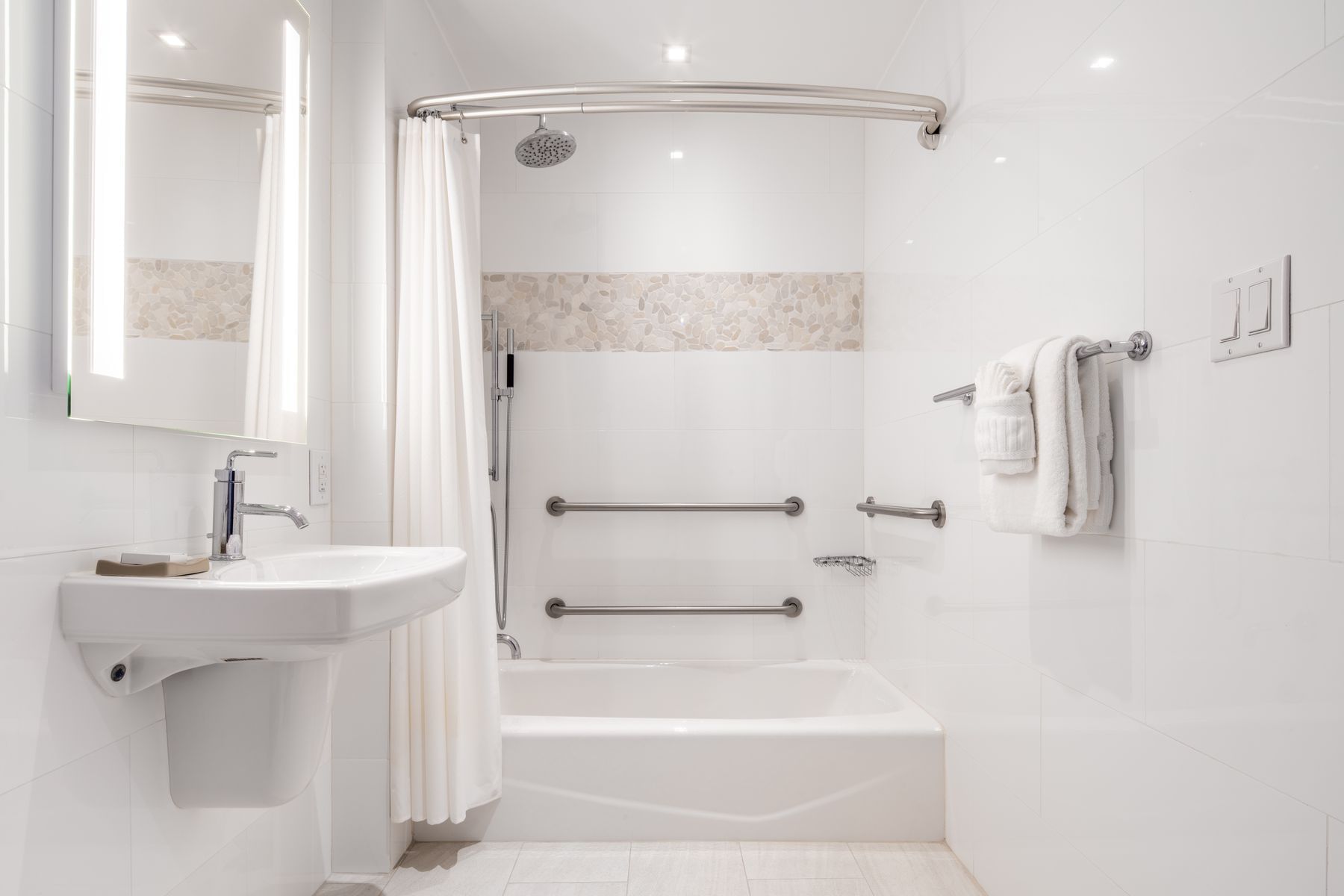 A clean and modern bathroom with a bathtub, shower, sink, and mirror.