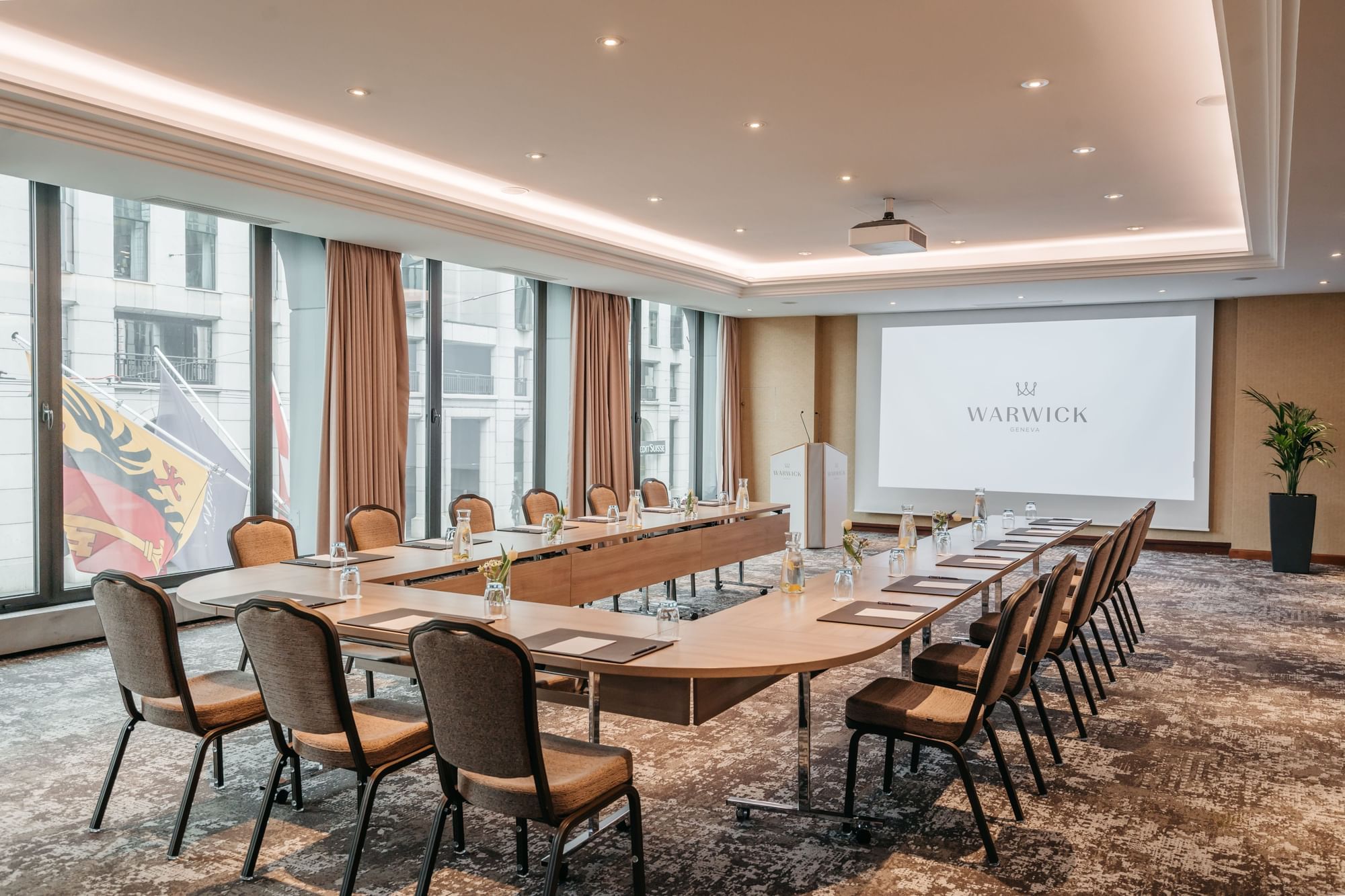 A long table with chairs and a city view in the Jura Meeting room at Warwick Geneva