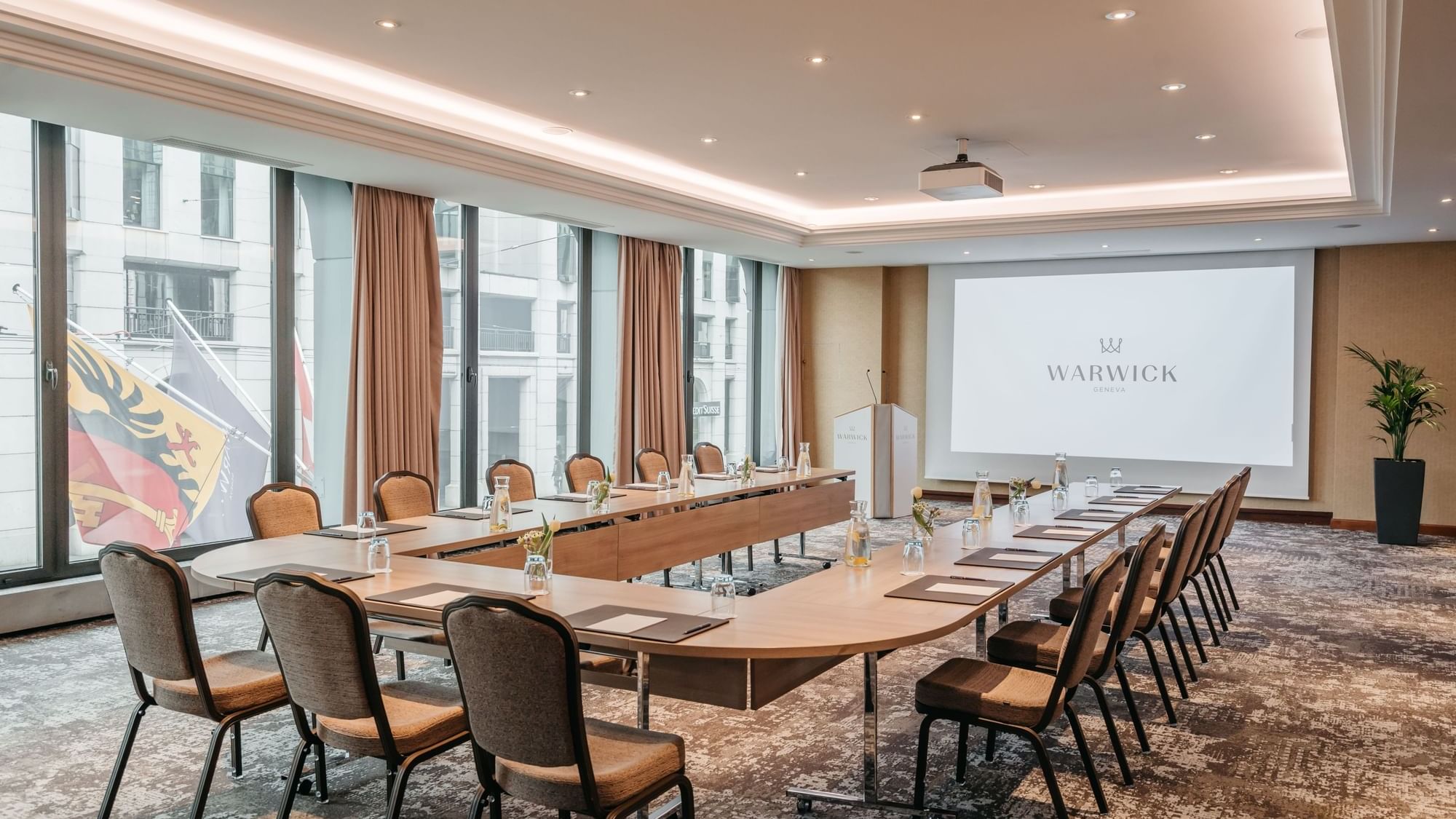 A long table with chairs and a city view in the Jura Meeting room at Warwick Geneva