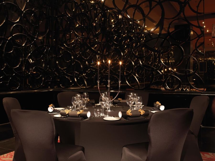 Dining setting featuring a round table with candles and luxurious black seating at The May Fair Hotel
