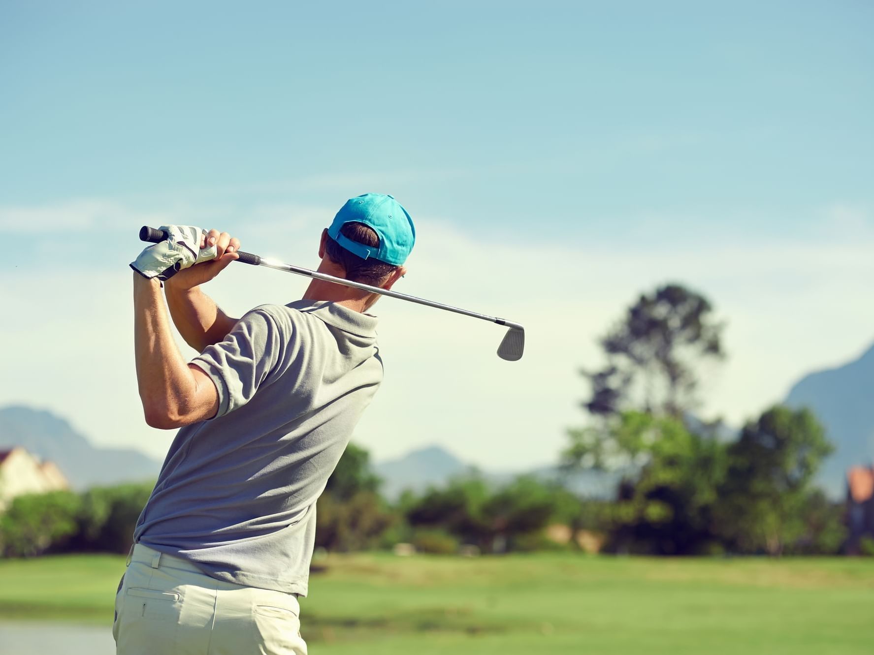 A golfer finishing his back swing after teeing off.