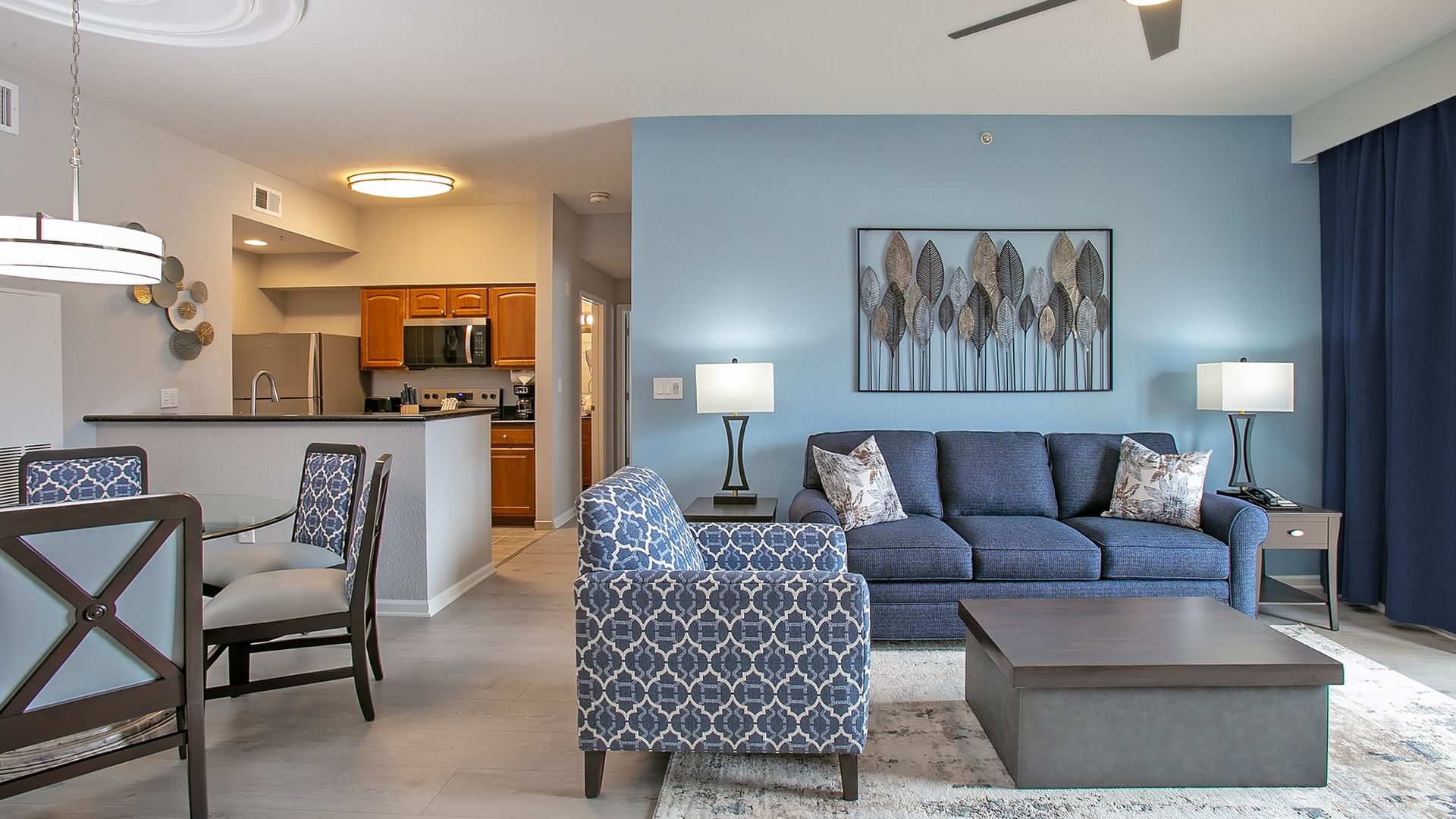A spacious living room with a kitchenette, dining area, and a comfortable seating area with a sofa, armchair, and coffee table.