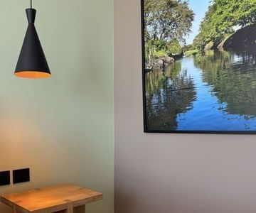Black pendant light above a wooden bedside table by framed river artwork at Unika Hotels, the best area to stay in Bogota