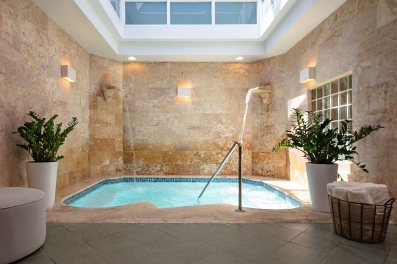 Soothing indoor hydrotherapy pool with wall waterfalls surrounded by potted plants at the Spa in El Conquistador Resort