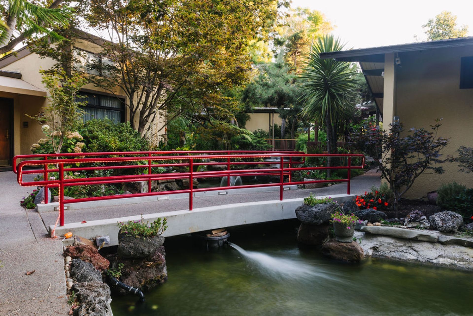 A bridge with a red railing at Dinah's Garden Hotel