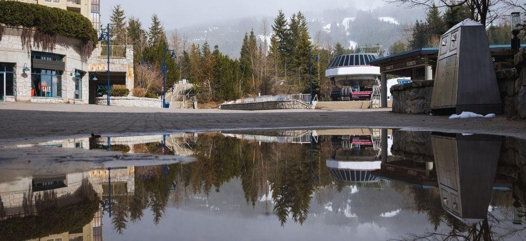 Whistler ski gondola and village area reflected in a puddle on a winter morning.