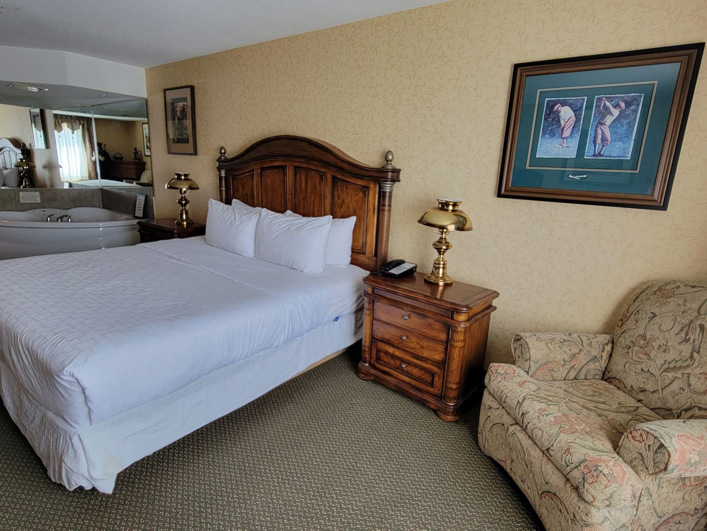 Lounger & jetted tub by bed in Golf Suite with carpeted floors at Merit Hotel & Suites