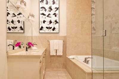 Bathroom vanity with fresh flowers, bathtub & towel rack in Presidential suite at Retro Suites Hotel