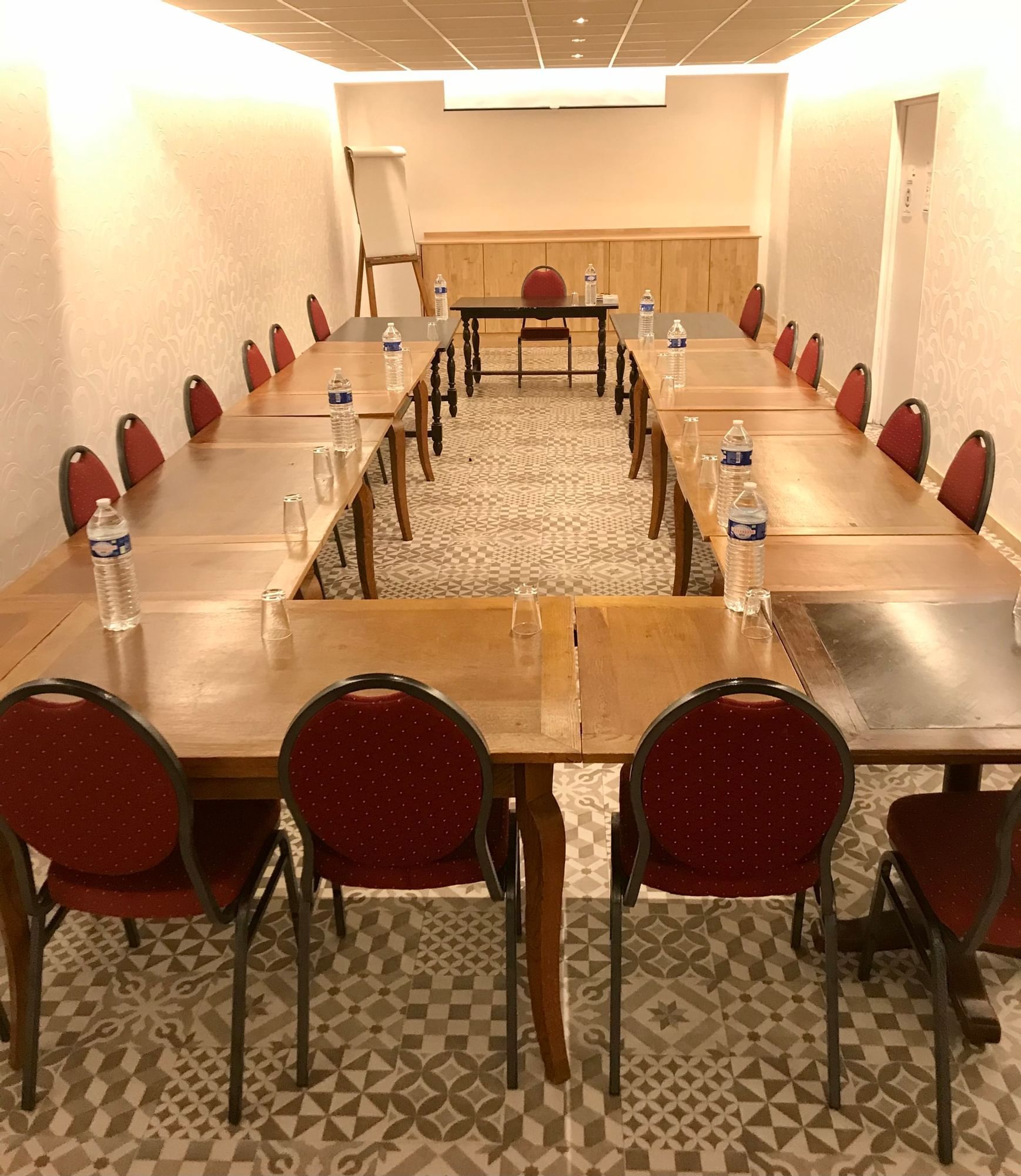 A hall arranged for a meeting with black tables and red chairs