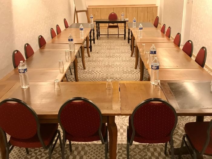 A hall arranged for a meeting with black tables and red chairs