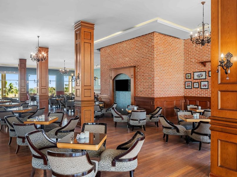 Elegant restaurant with wooden floors, brick walls, and numerous tables and chairs arranged in rows.