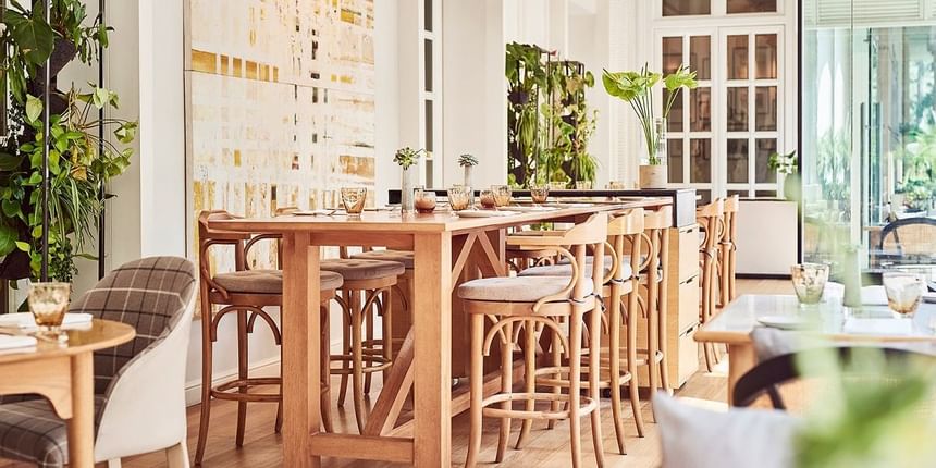 Elegant dining and lounge area with wooden accents and lush greenery in Opera at Park Hyatt Saigon