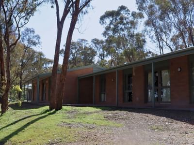 Row of brick villas with green roofs and glass windows surrounded by trees.