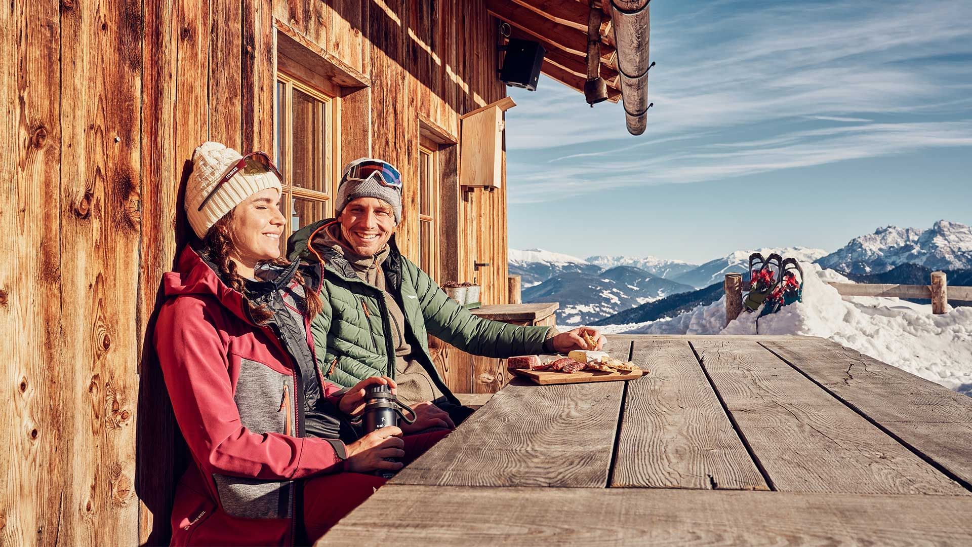 A cozy wooden cabin with two people enjoying a meal at Falkensteiner Hotel Kronplatz