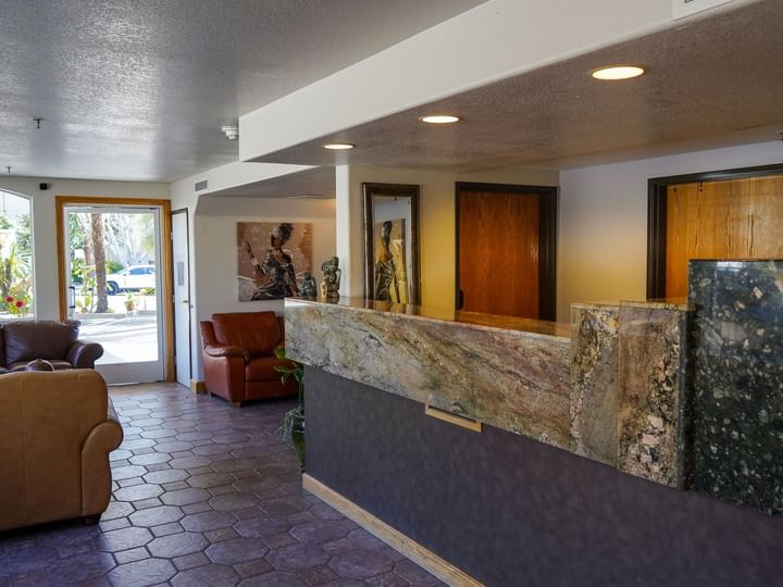 A hotel lobby with a reception desk, seating area, and doorway