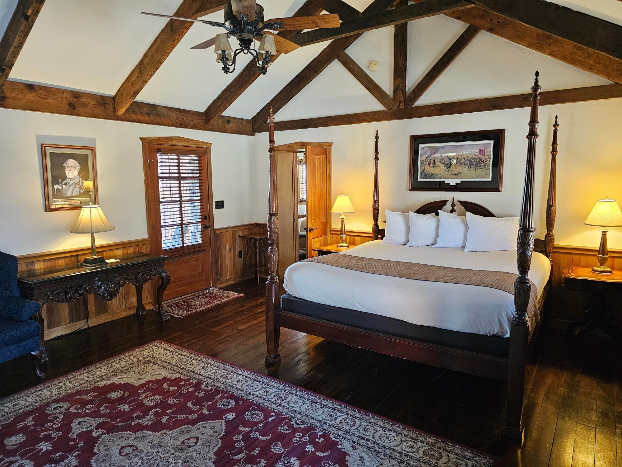 General's Lodge cozy bedroom with four-poster bed, wooden floors, and ceiling fan at The Lodges at Gettysburg.