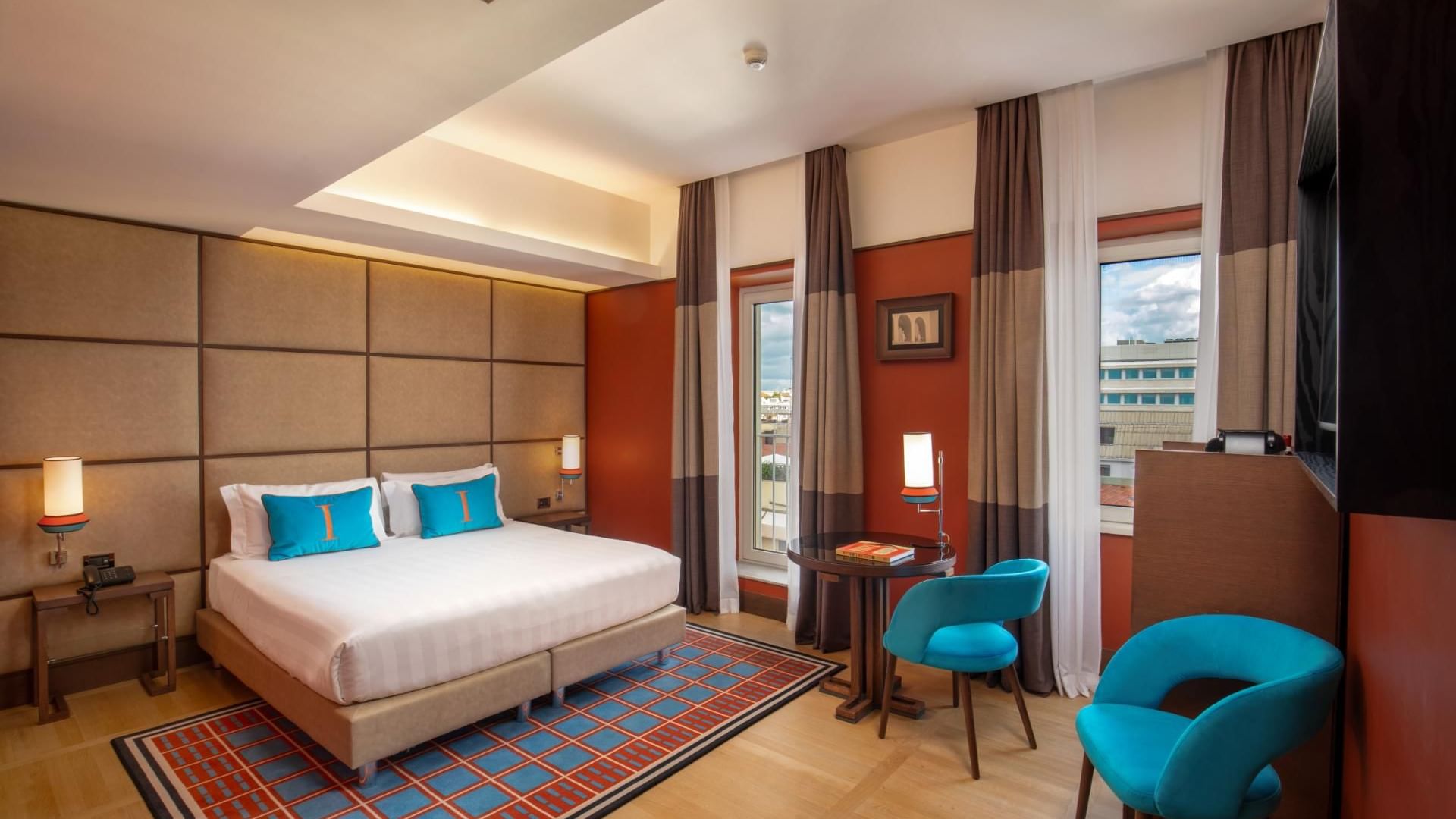 Modern Superior Room with a plush bed, wooden floors, and cozy seating by the window at The Independent