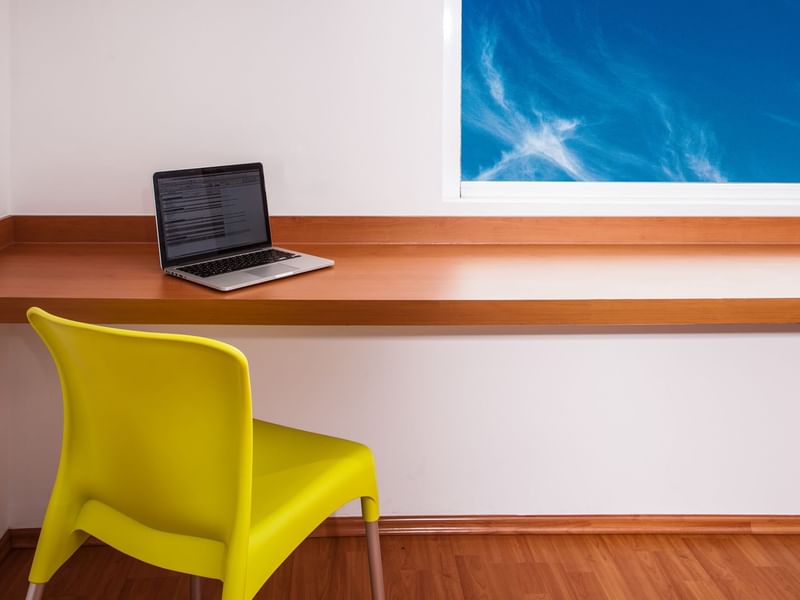 Laptop on a wall-mounted working desk with a chair, One Hotels