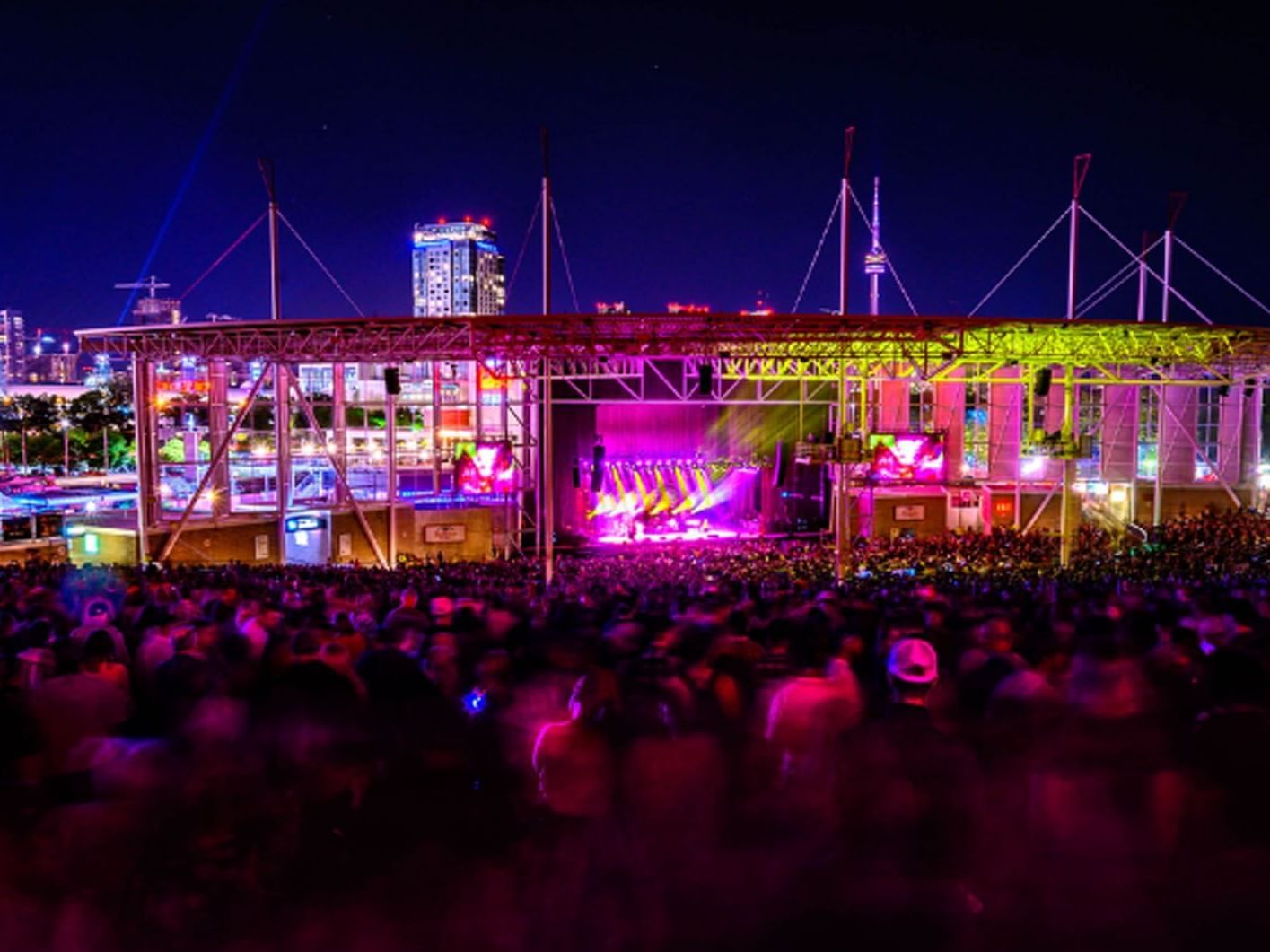Outdoor concert at night with stage lights, crowd, and city skyline by Budweiser Stage near Hotel X Toronto