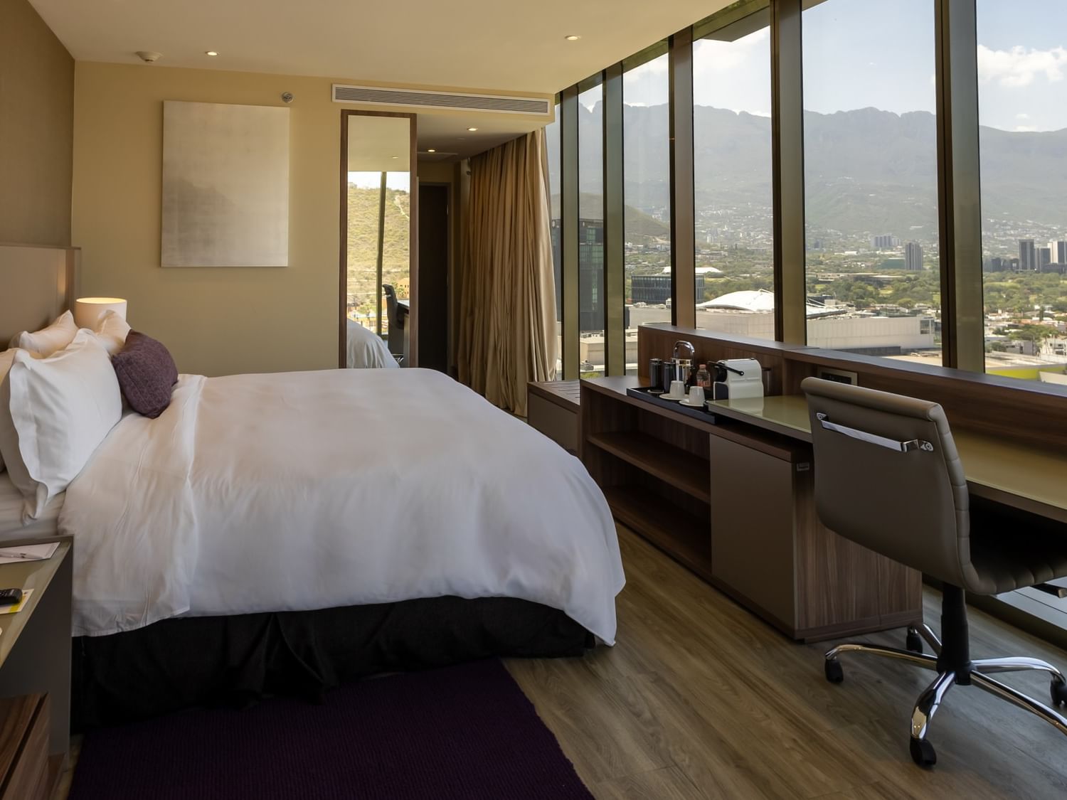 Junior Suite King con cama king, escritorio, ventanales amplios y vistas a la ciudad en Camino Real Fashion Drive Monterrey