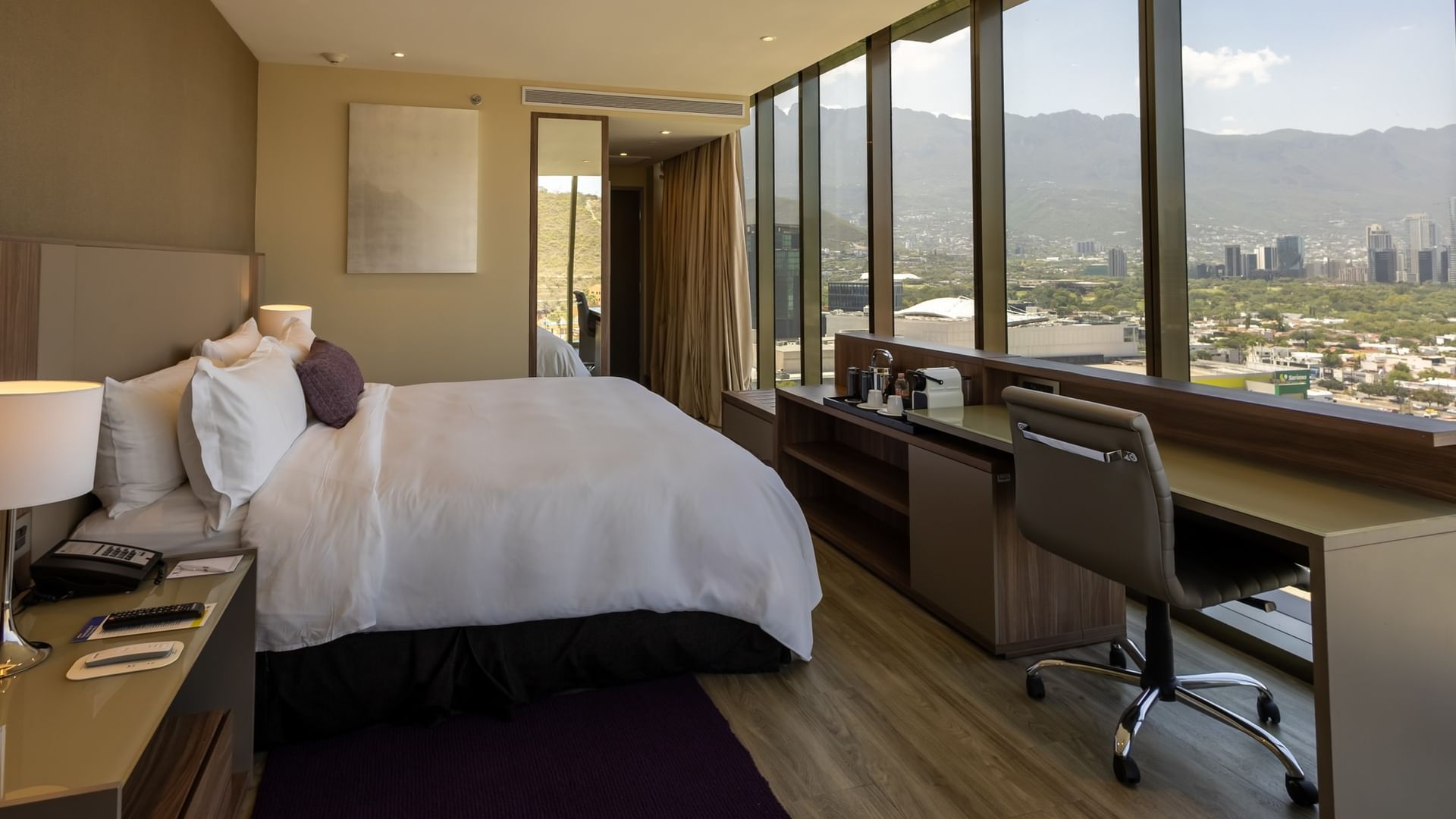 Junior Suite King con cama king, escritorio, ventanales amplios y vistas a la ciudad en Camino Real Fashion Drive Monterrey