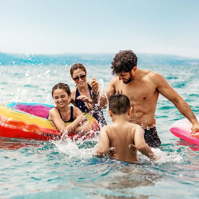 Famiglia felice giocando con i galleggianti nel mare blu sotto un cielo chiaro.