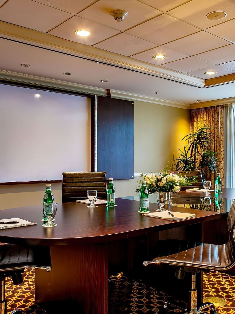 Leather office chairs by an oval table under a projector screen in Centennial at Warwick Denver