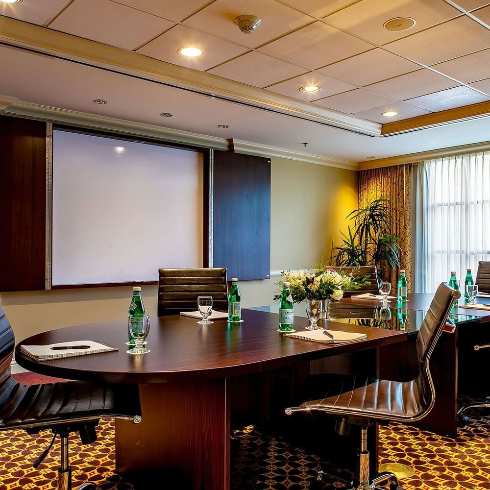 Leather office chairs by an oval table under a projector screen in Centennial at Warwick Denver