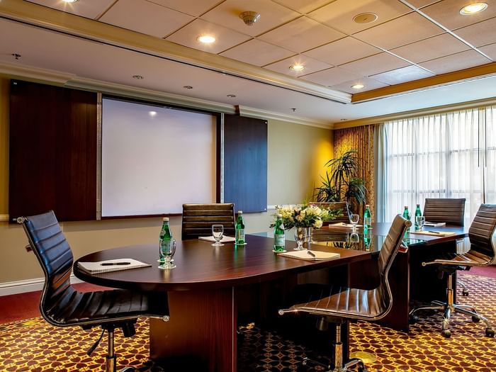 Leather office chairs by an oval table under a projector screen in Centennial at Warwick Denver