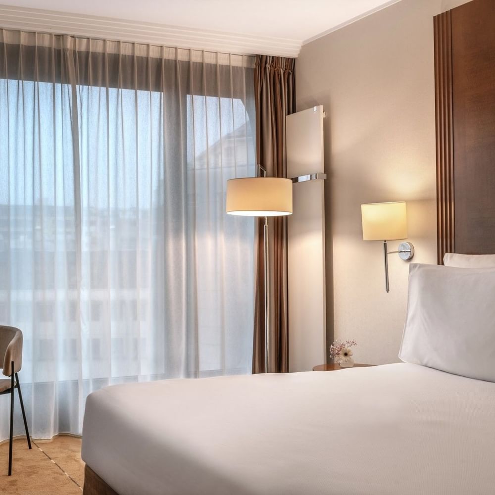 Superior Room with a work desk by a large window, under sheer curtains near a wall lamp at Warwick Geneva