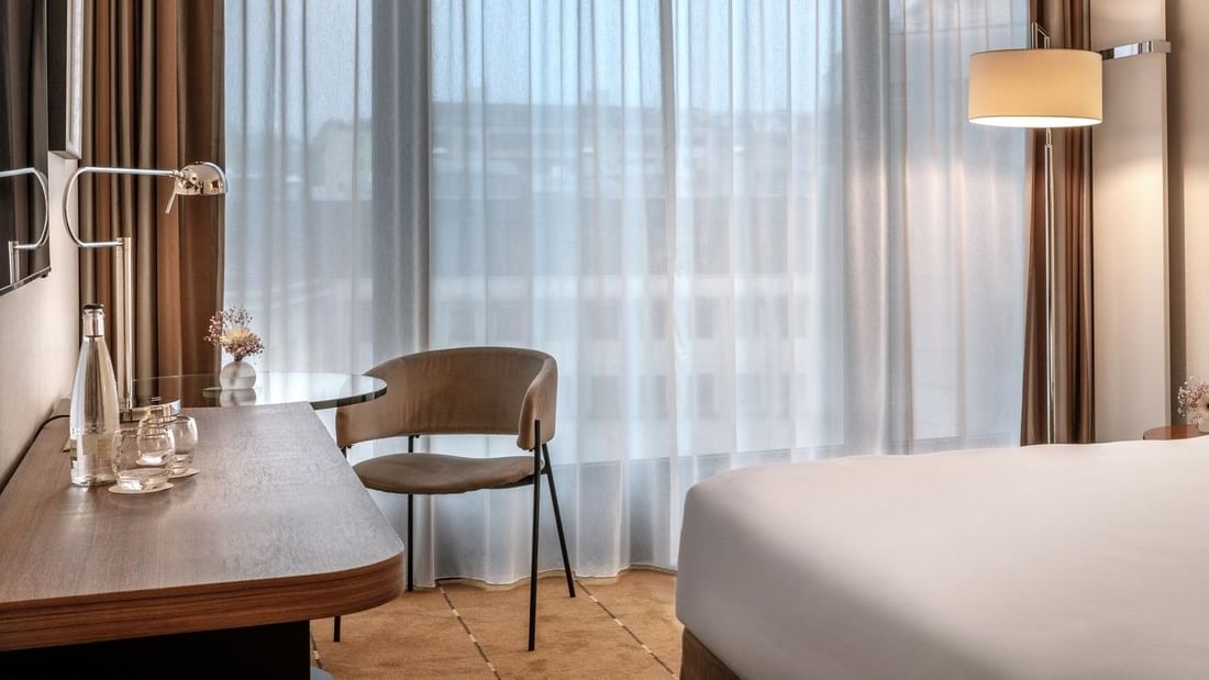 Superior Room with a work desk by a large window, under sheer curtains near a wall lamp at Warwick Geneva