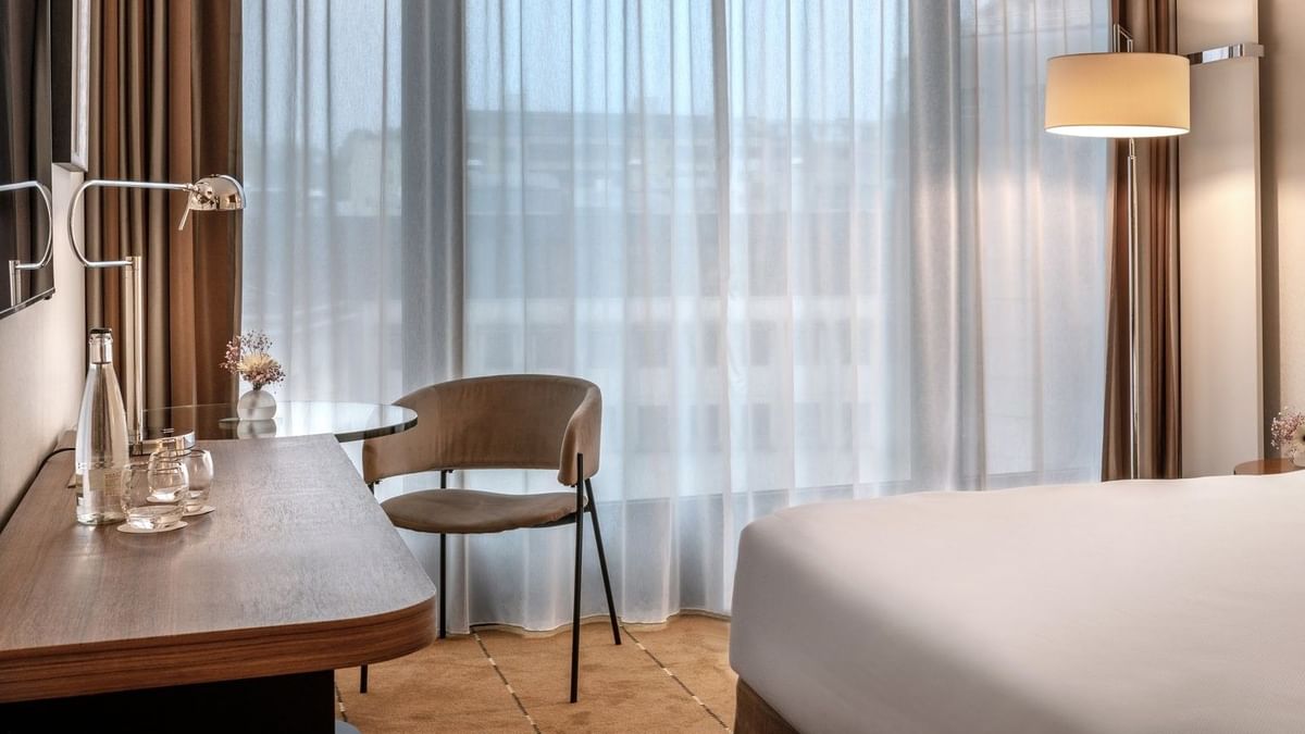 Superior Room with a work desk by a large window, under sheer curtains near a wall lamp at Warwick Geneva