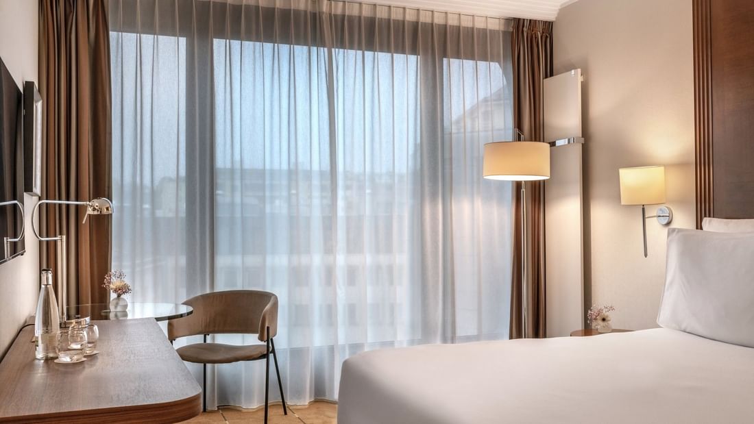 Élégante chambre Supérieure avec un grand lit, un fauteuil, un bureau et une fenêtre à l'hôtel Warwick Geneva à Genève.