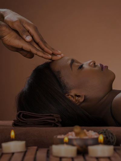 Person receiving a head massage in a relaxing spa setting with candles at Azalai Hotel Ouagadougou