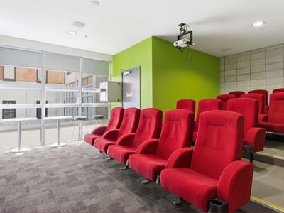 Red chairs in a room with green walls and projector at Student Living Auckland Anzac.