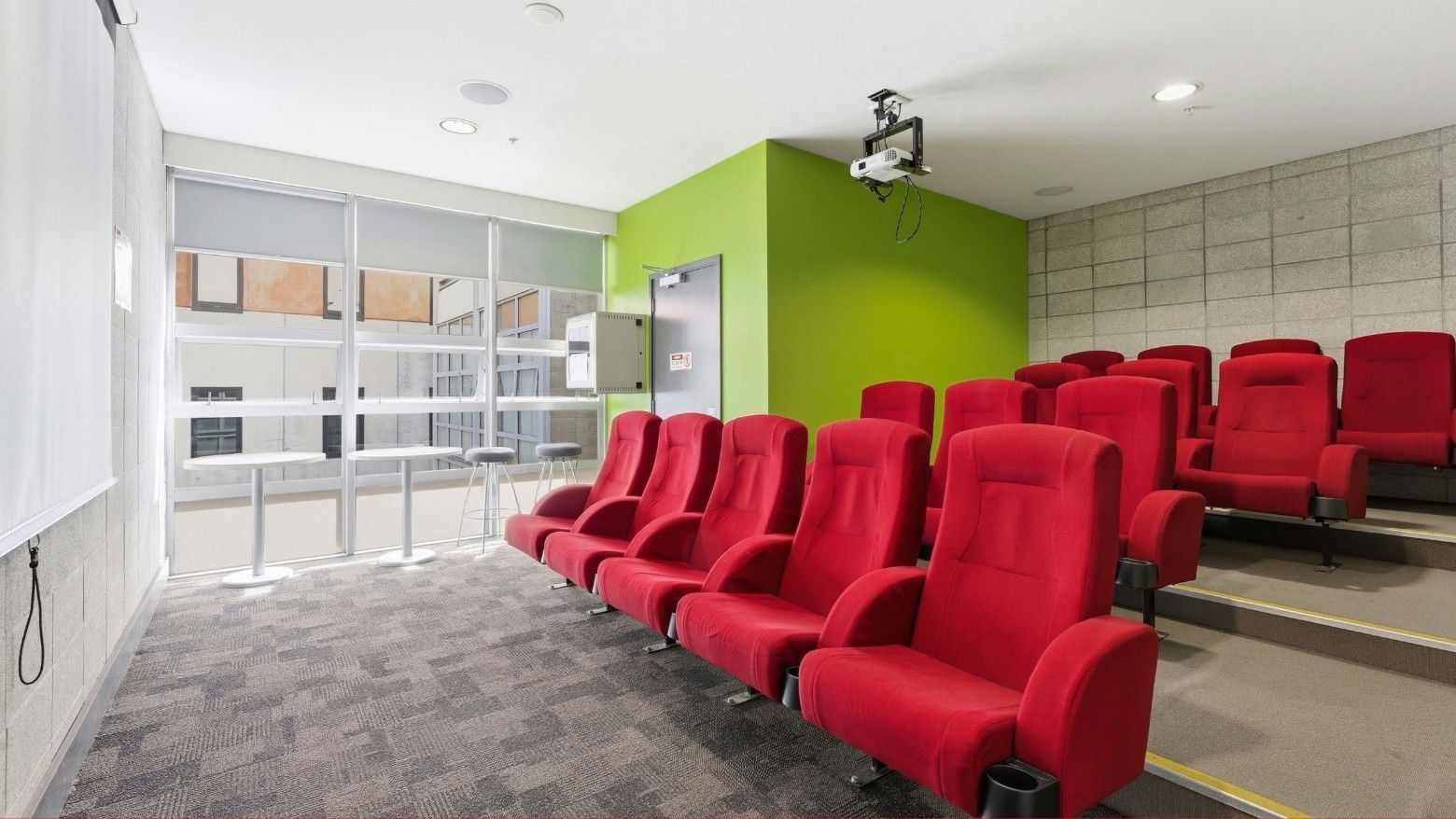 Red chairs in a room with green walls and projector at Student Living Auckland Anzac.