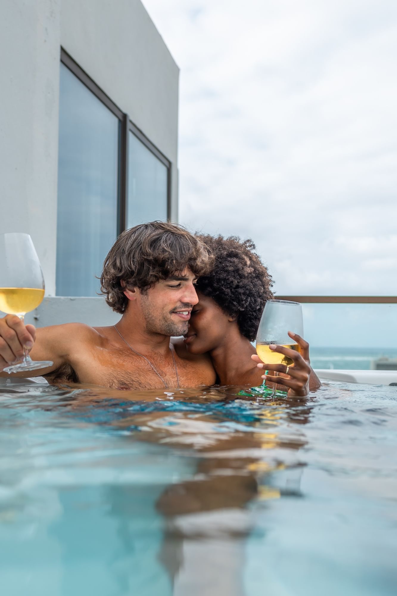 Couple enjoying wine in rooftop pool with ocean view at Hibird in Condado, San Juan, Puerto Rico.