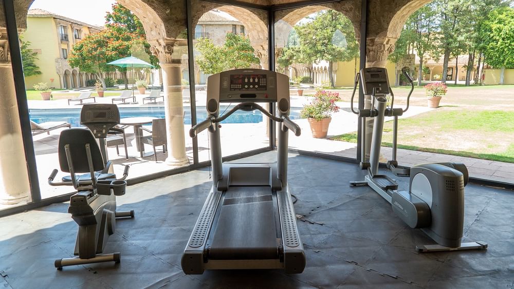 Fitness room with treadmills overlooking an outdoor pool at Quinta Real Aguascalientes