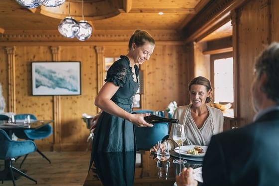 A waitress serving champagne to a couple at Hotel Liebes Rot