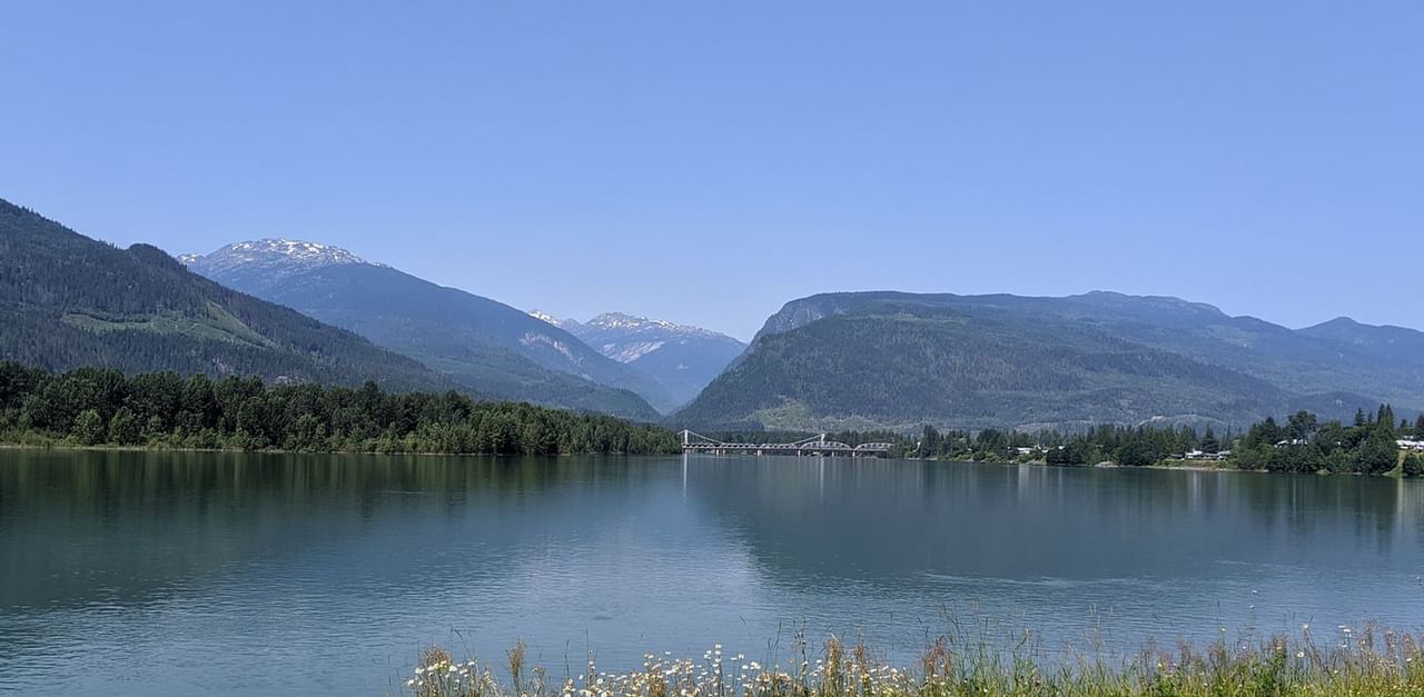 photo of a lake with mountains and a bridge in the background