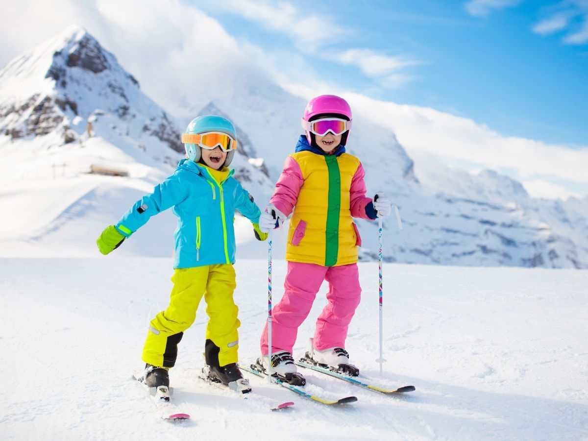 Kids in ski kits preparing to skiing on snowy pathway near Blackcomb Springs Suites