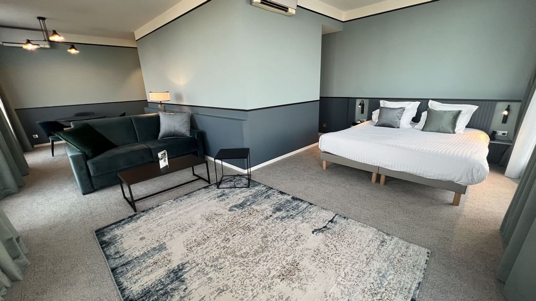 Chambre élégante avec lit double, canapé, table basse et climatiseur mural dans un espace bien décoré.